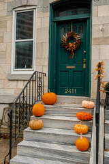 Interior ready for trick or treat party or Thanksgiving. Halloween decorated front door with various size and shape pumpkins. Home entrance decorated. Pumpkin lantern at house front door.