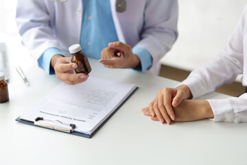 Doctor write prescription and advise patient to use medicine in hospital examination room, treatment the disease with medicine from a specialist. Concept of medical treatment and health consultation.