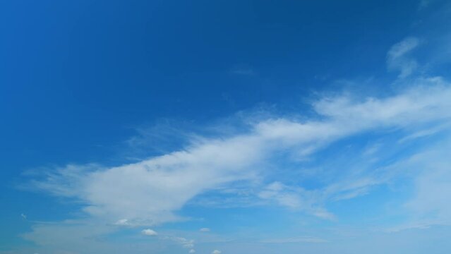 Flying moving white clouds in a blue sky. Blue sky background with many layers tiny stratus cirrus clouds. Time lapse.