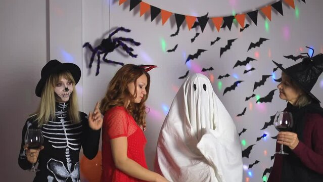 Halloween Costume Party. she-devil, witch, ghost dancing in a decorated room.