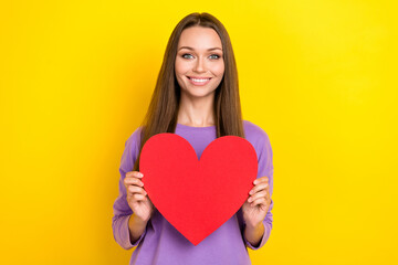 Photo of cheerful nice lady toothy smile wear trendy clothes arms hold red paper heart charity event isolated on yellow color background