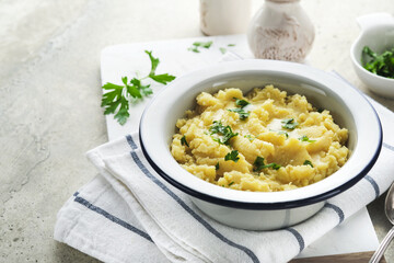 Mashed potatoes. Hot mashed potatoes with butter, fresh parsley herbs and pepper in bowl on slate, stone or concrete backgrounds. Delicious creamy mashed potatoes. Top view.