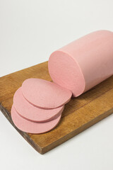 Boiled sausage on a wooden board on a white background. Sliced boiled sausage.