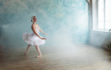 Fototapeta na wymiar a professional ballerina in a white tutu is dancing in a room with blue wall and smoke