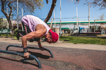Healthy and fit young latin man with tattooed upper arm and shoulder, cap and purple shirt doing...