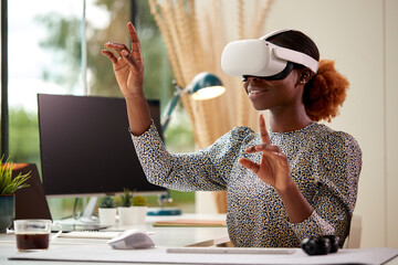 Woman Working From Home Office Sitting At Desk Wearing VR Headset Interacting With AR Technology