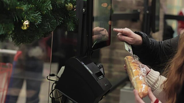 Customer uses touch panel at self-service checkout ACO. Buyer manually enters product name or barcode number. Assisted checkout SCO with cashless payment. Shopping at mall and store. Self-checkout