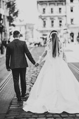 A loving wedding couple are walking back along the streets of the city of Lviv