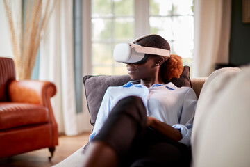 Woman Relaxing Lying On Sofa At Home Wearing VR Headset And Interacting With AR Technology