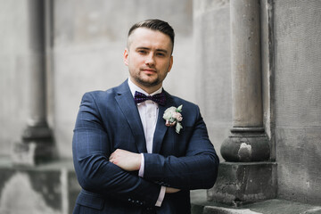 Happy handsome smiling groom posing with boutonniere