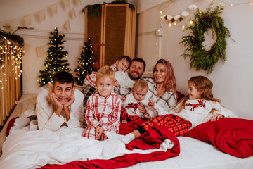 Big family of seven in winter pyjamas having fun in the bedroom with Christmas decor. Holiday...