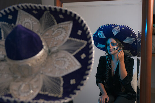 Young woman puts on makeup to disguise herself for Mexico day of the dead