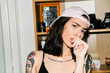 Woman with tattoos black hair looking at camera in an intense way.