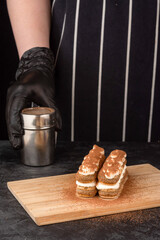 Making dessert tiramisu cake on a dark background