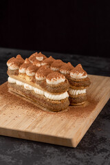 Dessert Tiramisu cake on a tray on a dark background
