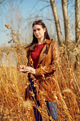 Outdoor portrait of beautiful woman in leather jacket. Thickets of dried grass