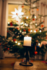 candle with christmas tree unfocused in the background