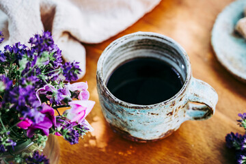 Café noir dans une tasse en grès à la maison avec un bouquet de fleurs champêtre - Ambiance...