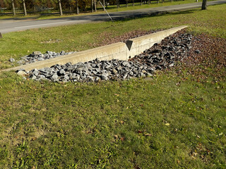 Example image of a concrete v notch weir, level spreader, located adjacent to a highway swale. 