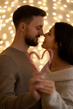 Holiday loving family portrait kissing and showing candy heart with bokeh lights in background. Focus on couple