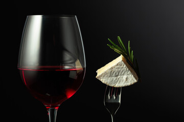 Glass of red wine and Camembert cheese with rosemary.