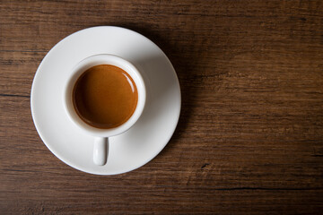 White cup of espresso with coffee beans on wooden background,top view