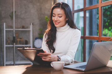 Asian Female consultant, designer or achitect is writing a plan for work in the coffee shop while...