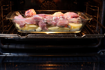 bandeja de carne al horno cruda con base de patatas y cebolla, receta de carne de conejo y cabrito