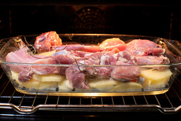 bandeja de carne al horno cruda con base de patatas y cebolla, receta de carne de conejo y cabrito