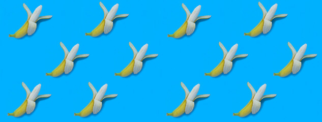 Yellow peeled bananas on the blue background. Pattern. Flat lay.