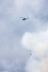 Wildfire Service Helicopter flying over BC Forest Fire and Smoke on the mountain near Hope during a hot sunny summer day. British Columbia, Canada. Natural Disaster