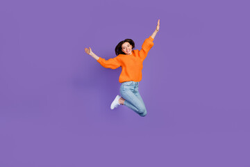 Fototapeta na wymiar Full length photo of adorable young lady jumping high sportive wear trendy orange knitwear clothes isolated on violet color background