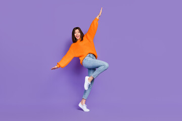 Full body photo of pretty young girl have fun dancing hands wings wear trendy orange knitwear outfit isolated on violet color background