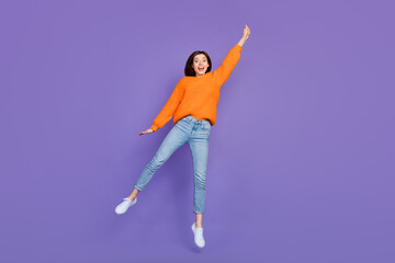 Fototapeta na wymiar Full length photo of lovely young lady hang invisible umbrella wear trendy orange knitwear clothes isolated on violet color background