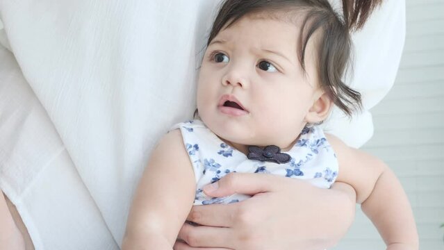 Baby girl was held by her mother flinched by the sound of door closing.