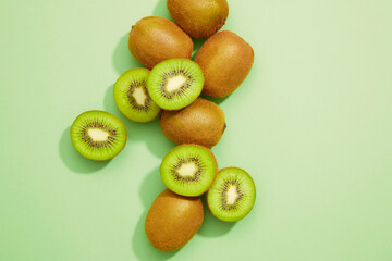 Obraz premium Fresh kiwi with a slice fruit on a green background. Summer weather, green living, healthy life