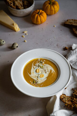 Homemade pumpkin cream soup with quail eggs, parmesan , sour cream and pistachios and biscotti with dried tomatoes and pistachios on white background 