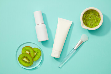A light blue background is adorned with a sample cream tube, an empty sample bottle, kiwi slices in a transparent plate, and a bowl of kiwi mask. Take a label.
