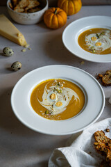 Homemade pumpkin cream soup with quail eggs, parmesan , sour cream and pistachios and biscotti with dried tomatoes and pistachios on white background 