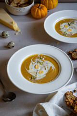 Homemade pumpkin cream soup with quail eggs, parmesan , sour cream and pistachios and biscotti with dried tomatoes and pistachios on white background 