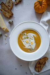 Homemade pumpkin cream soup with quail eggs, parmesan , sour cream and pistachios and biscotti with dried tomatoes and pistachios on white background 
