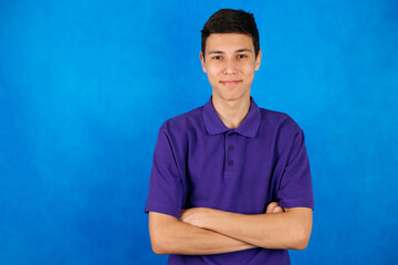 Close-up portrait of a young man, a teenager on a blue background, smiling beautifully at the camera