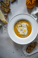 Homemade pumpkin cream soup with quail eggs, parmesan , sour cream and pistachios and biscotti with dried tomatoes and pistachios on white background 