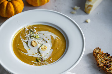 Homemade pumpkin cream soup with quail eggs, parmesan , sour cream and pistachios and biscotti with dried tomatoes and pistachios on white background 