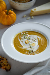 Homemade pumpkin cream soup with quail eggs, parmesan , sour cream and pistachios and biscotti with dried tomatoes and pistachios on white background 
