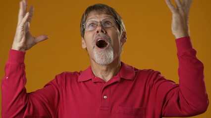 Angry, scared mature man 50s posing isolated on yellow background studio. People lifestyle concept. Spreading arms screaming crying ask why me