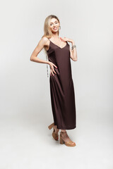 Fashion happy pretty woman blonde model in stylish vintage brown strappy dress with shoes on a white background