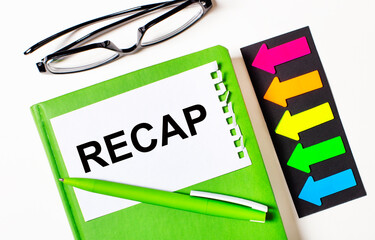 On a light background, multi-colored arrows, black glasses, a green notebook with a pen and a white...