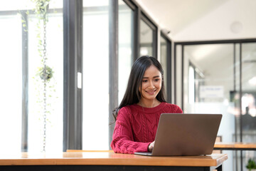 Young asian businesswoman beautiful charming smiling and using laptop computer in office.