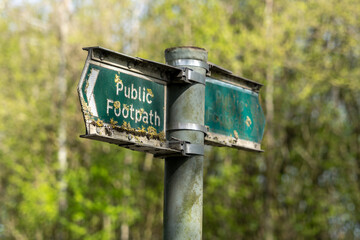 Old green public footpath sign with moss and litchen growing over